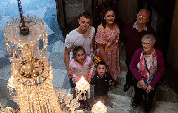 Family inside castle hall looking up at impressive chandelier.