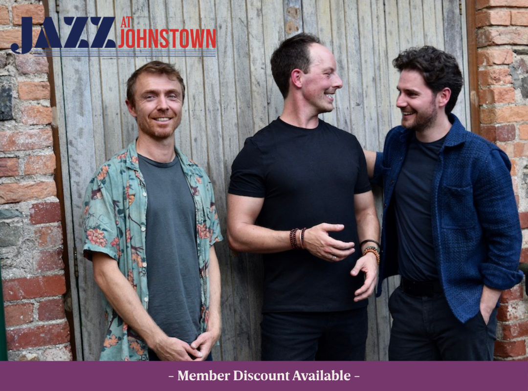 Johnny Taylor Trio Johnny Taylor, Dominic Mullan and Barry Donohue talking together in front of an old brick backdrop.