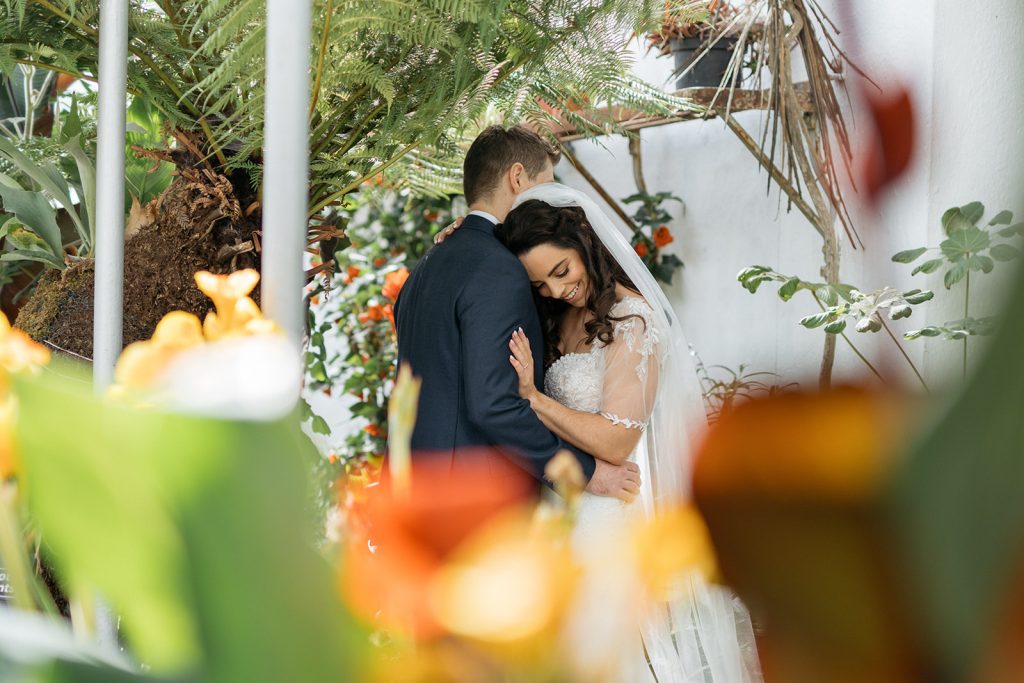 Wedding couple embracing in the glass house of johnstown castle. 