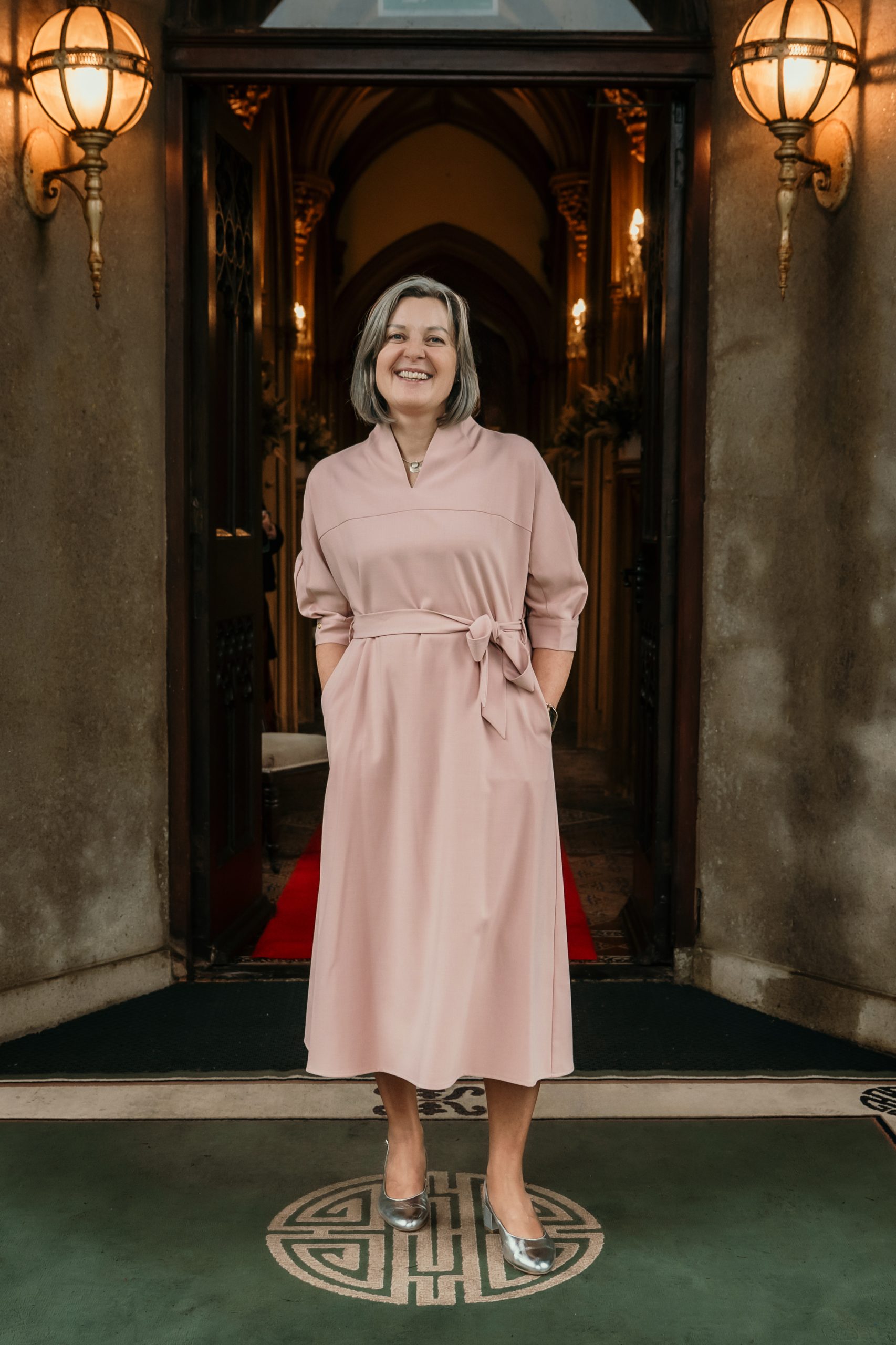 Judy Dunwoody, the Johnstown Castle Wedding Coordinator. Judy is standing at the front entrance to the castle with a red carpet entrance. 